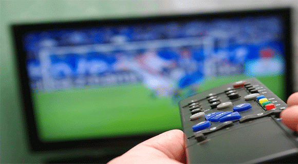 Viewer Holding Remote Control Watching Soccer On Connected-TV